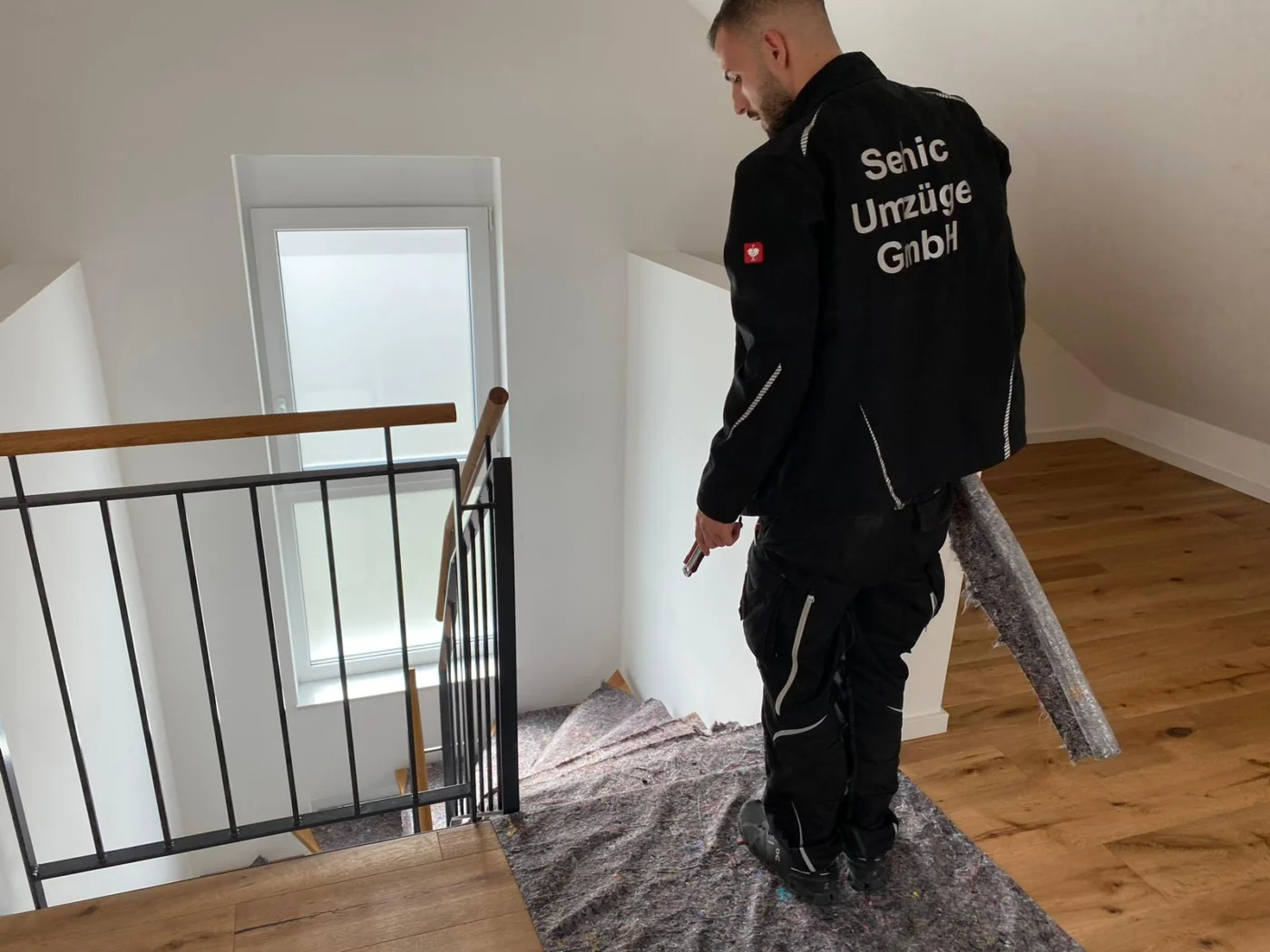 Mitarbeiter von Sehic Umzüge sichert das Treppenhaus mit Bodenschutz vor dem Fernumzug