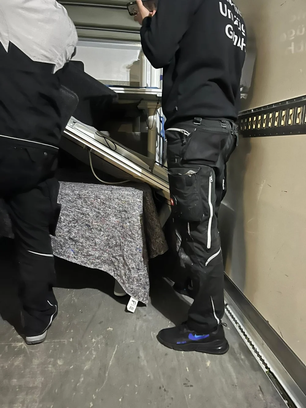 Zwei Möbelpacker von Sehic Umzüge verladen ein eingepacktes Möbelstück beim Möbeltransport in Karlsruhe