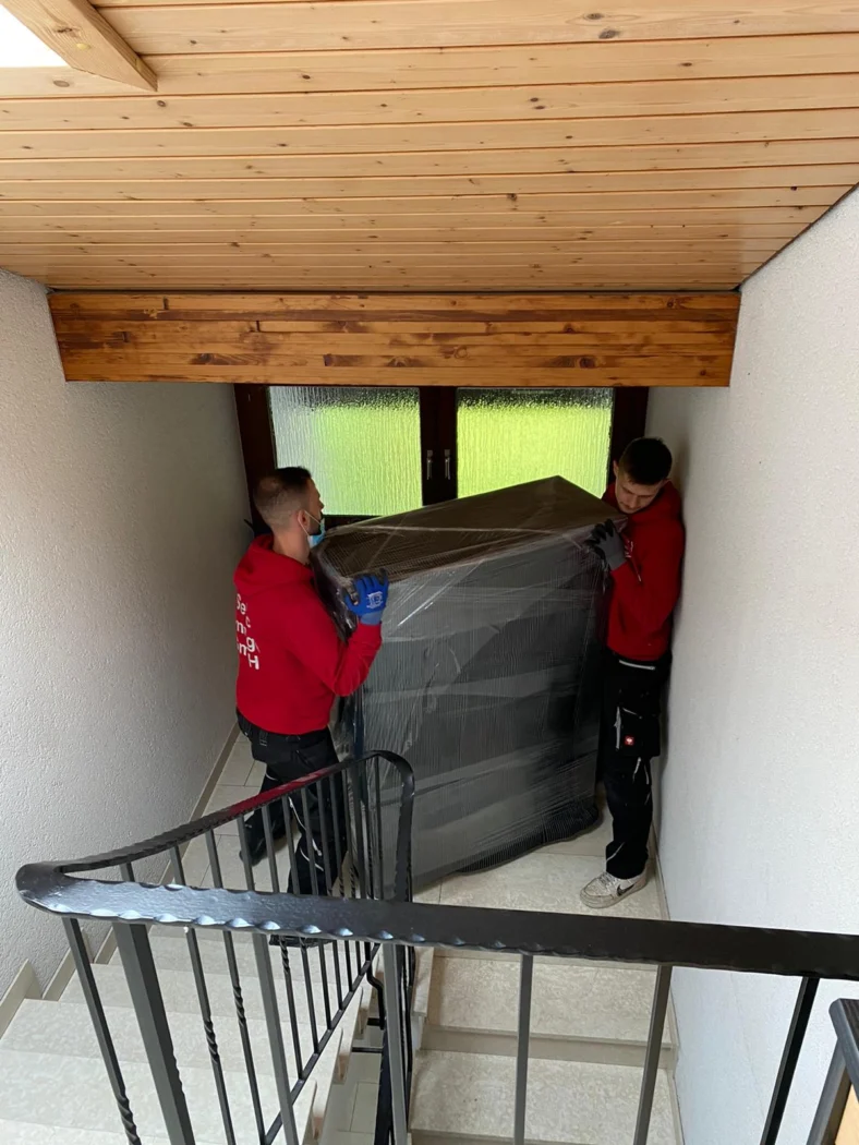 Möbelpacker tragen ein großes Möbelstück durch ein enges Treppenhaus in Karlsruhe