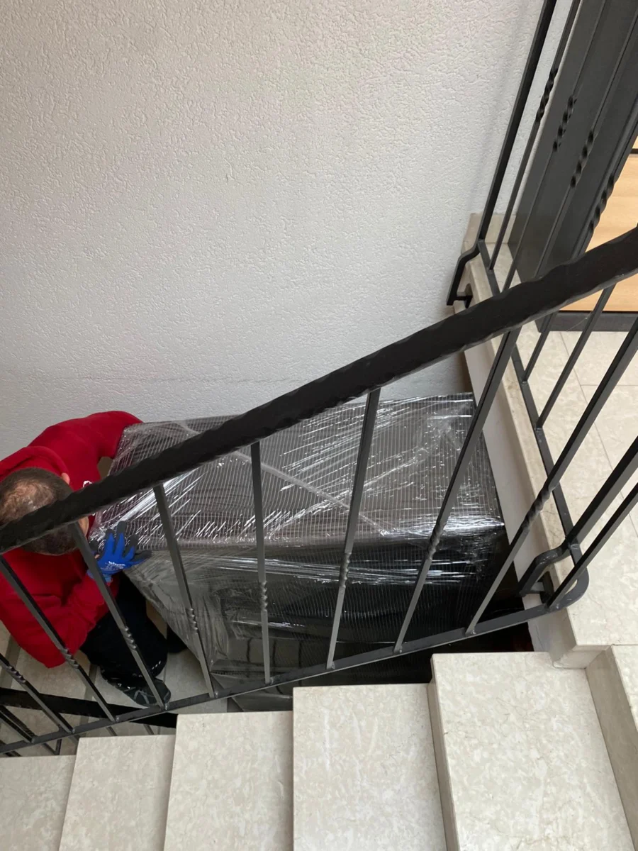 Eingepacktes Möbelstück wird beim Umzug von Karlsruhe nach Hamburg über die Treppe getragen