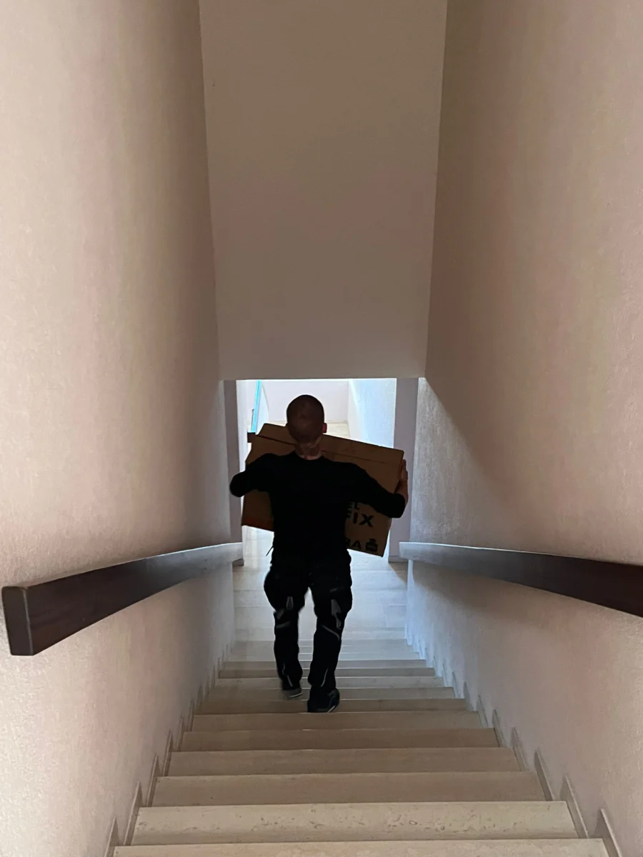 Möbelpacker trägt Umzugskartons die Treppe hinunter beim Umzug von Karlsruhe nach München